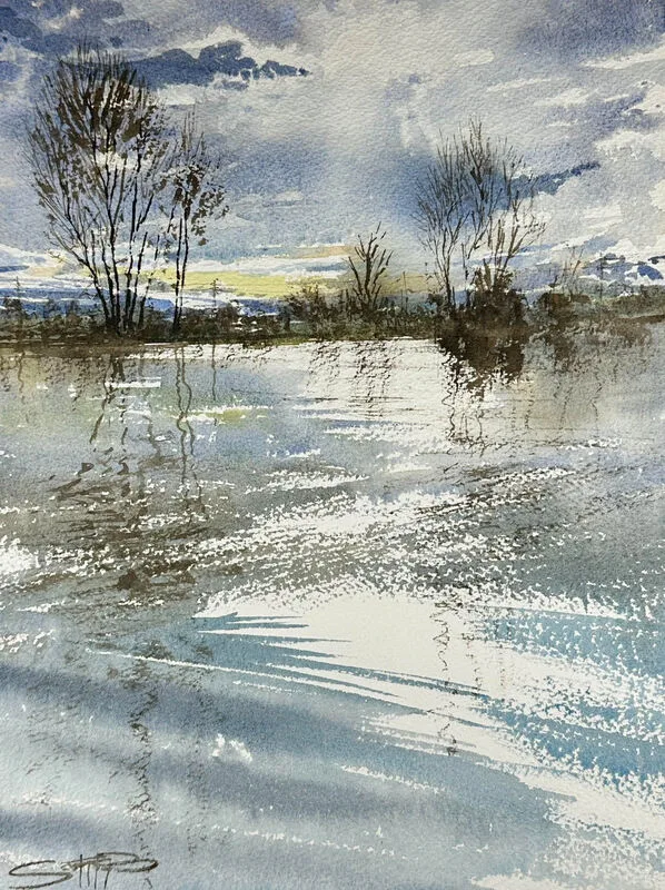 A wintery scene painted in watercolour showing bright sunlight coming through the clouds and reflecting in glassy water, bare trees in the background.