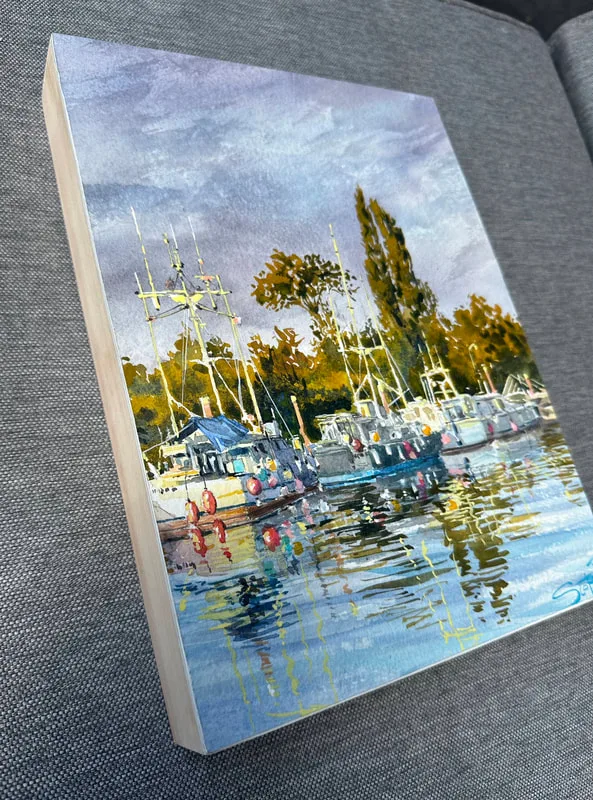 A watercolour painting of scotch pond in Steveston, BC. Afternoon golden sunlight lights up the water reflection fishing boats with colourful buoys attached. Trees behing and a stormy greay sky.